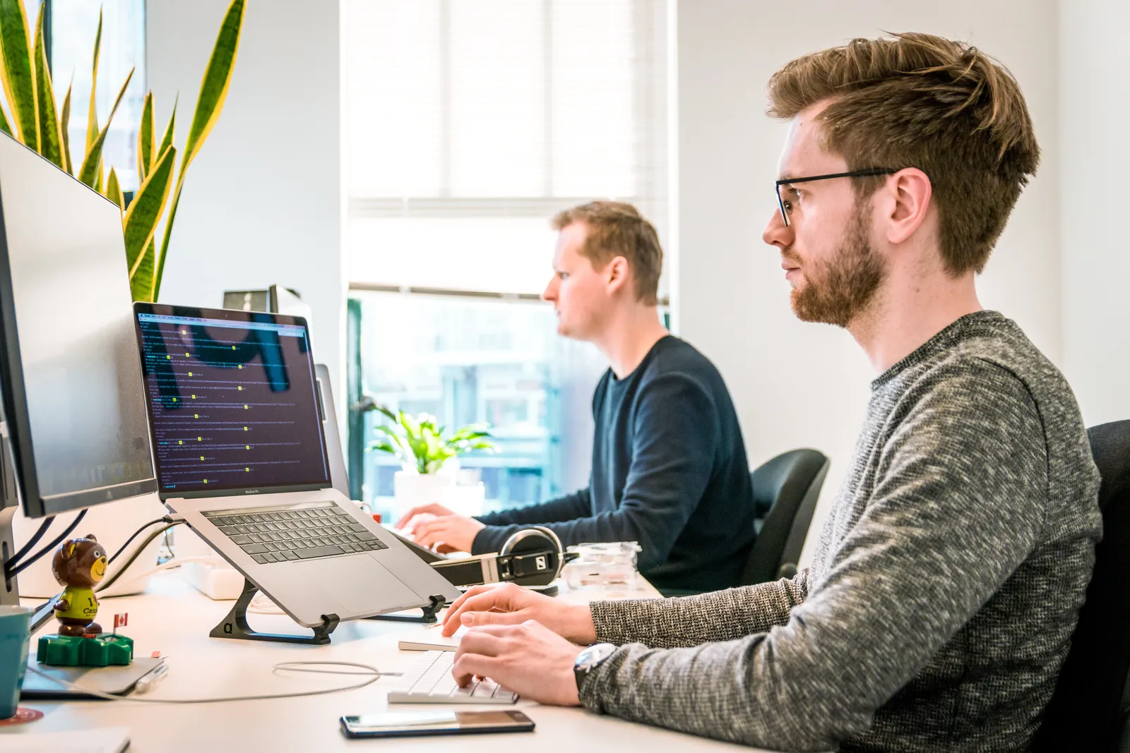 Zwei Mitarbeiter arbeiten konzentriert an Computern in einem hellen Büro